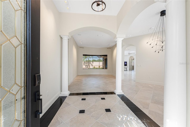 hallway featuring baseboards, ornate columns, and arched walkways