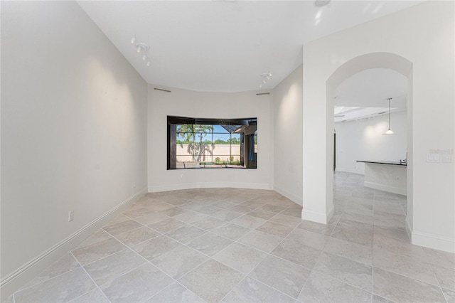 spare room featuring arched walkways and baseboards