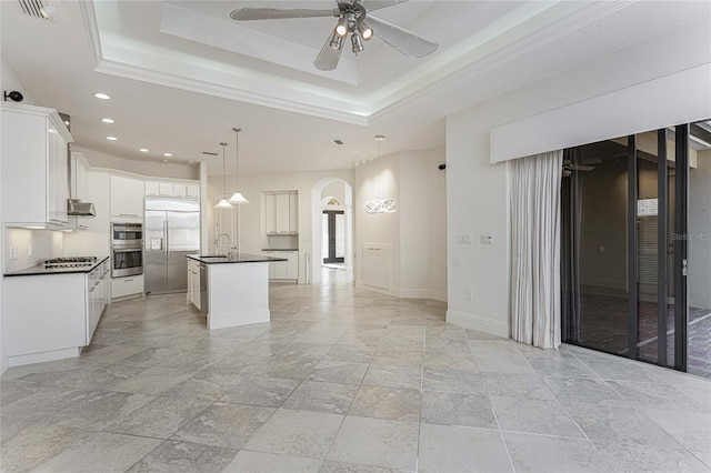 kitchen with recessed lighting, dark countertops, appliances with stainless steel finishes, stone tile floors, and a sink