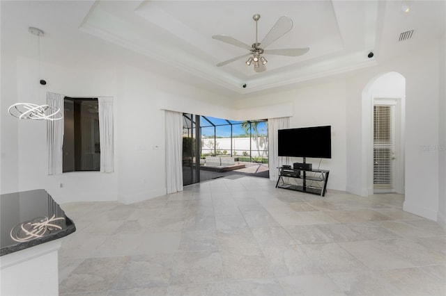 unfurnished living room with baseboards, visible vents, a tray ceiling, ceiling fan, and arched walkways
