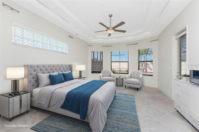 bedroom with multiple windows, ceiling fan, and a raised ceiling