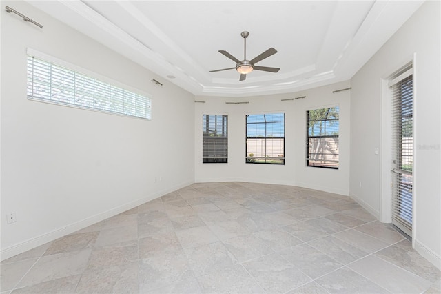 spare room with a raised ceiling, ceiling fan, baseboards, and plenty of natural light