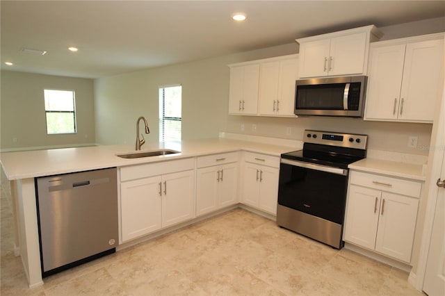 kitchen featuring a peninsula, appliances with stainless steel finishes, a sink, and a healthy amount of sunlight