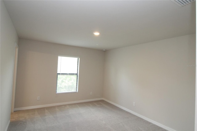 spare room with baseboards, recessed lighting, and light carpet