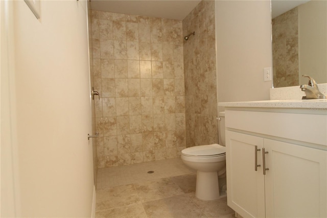 bathroom with toilet, tiled shower, and vanity