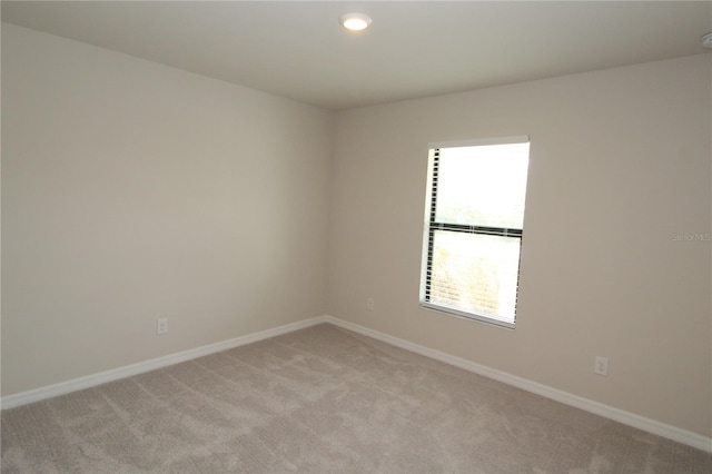 unfurnished room featuring light colored carpet and baseboards