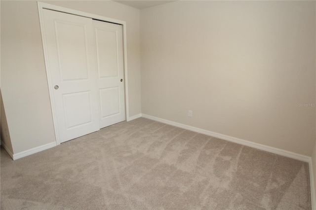 unfurnished bedroom featuring a closet, baseboards, and carpet floors