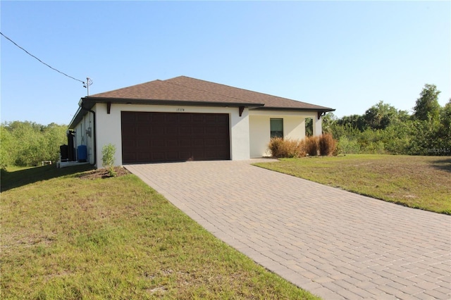 view of front of property featuring a front yard, decorative driveway, a garage, and stucco siding