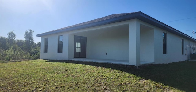 rear view of house featuring a yard and stucco siding
