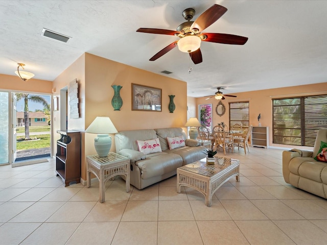 living area featuring light tile patterned floors, a ceiling fan, and visible vents
