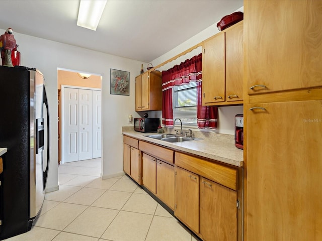 kitchen featuring stainless steel fridge with ice dispenser, light tile patterned floors, a sink, light countertops, and black microwave