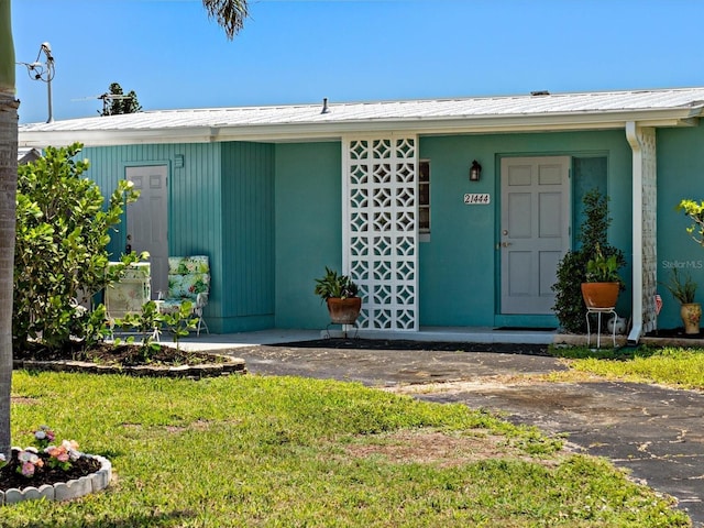 entrance to property featuring a yard and metal roof