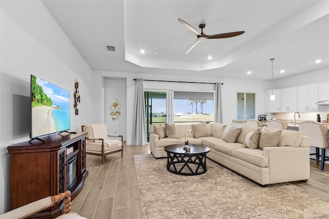 14413 Heritage Landing Blvd, Punta Gorda, FL 33955 - living room with a ceiling fan, light wood-style floors, a tray ceiling, and recessed lighting