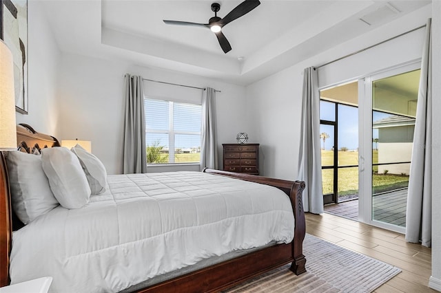 14413 Heritage Landing Blvd, Punta Gorda, FL 33955 - bedroom with access to outside, wood finished floors, a tray ceiling, and a ceiling fan