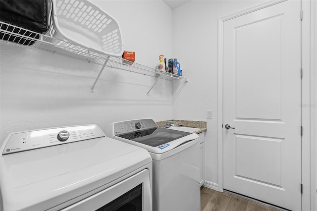 14413 Heritage Landing Blvd, Punta Gorda, FL 33955 - washroom with washer and clothes dryer, wood finished floors, and cabinet space