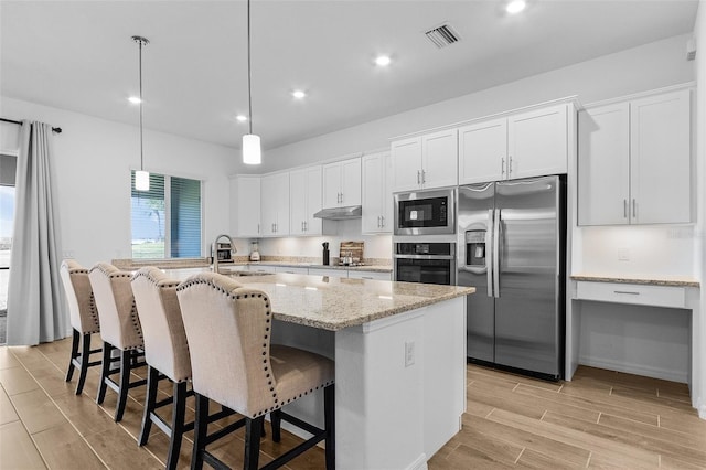 14413 Heritage Landing Blvd, Punta Gorda, FL 33955 - kitchen with appliances with stainless steel finishes, a sink, an island with sink, white cabinetry, and wood finish floors