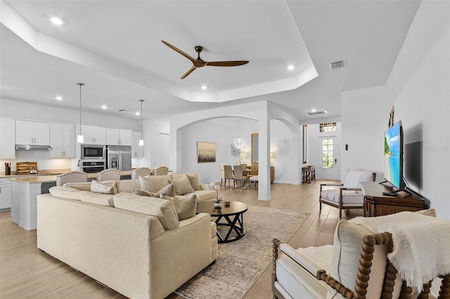 14413 Heritage Landing Blvd, Punta Gorda, FL 33955 - living room featuring arched walkways, a raised ceiling, recessed lighting, ceiling fan, and light wood-style floors