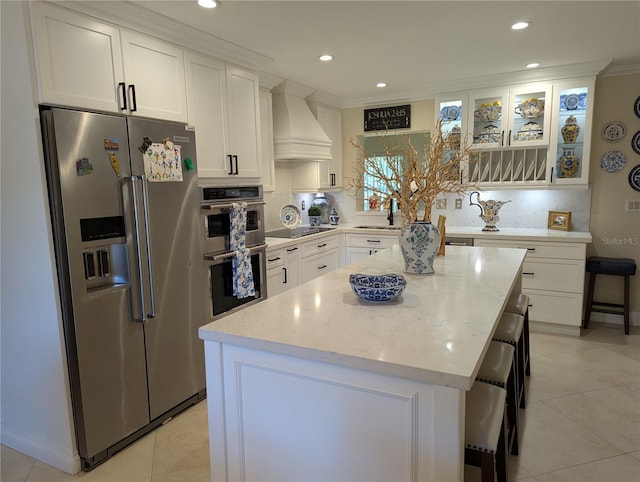 1233 Dewhurst St, Port Charlotte, FL 33952 - kitchen with custom range hood, light tile patterned floors, a center island, white cabinetry, and appliances with stainless steel finishes