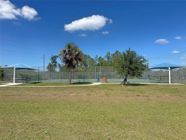 surrounding community with fence, a yard, and a tennis court