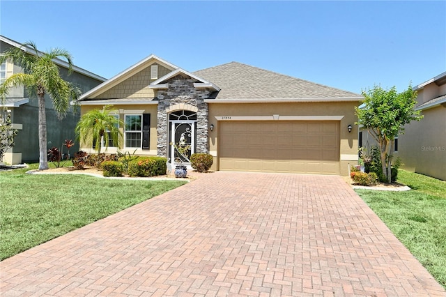 view of front facade with decorative driveway, a front yard, a garage, stucco siding, and roof with shingles