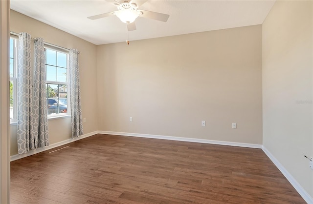 empty room with baseboards, a ceiling fan, and dark wood-style floors