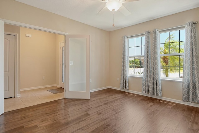 unfurnished room with wood finished floors, baseboards, and ceiling fan