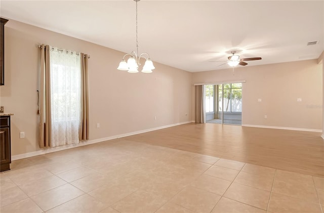empty room with light tile patterned flooring, visible vents, baseboards, and ceiling fan with notable chandelier