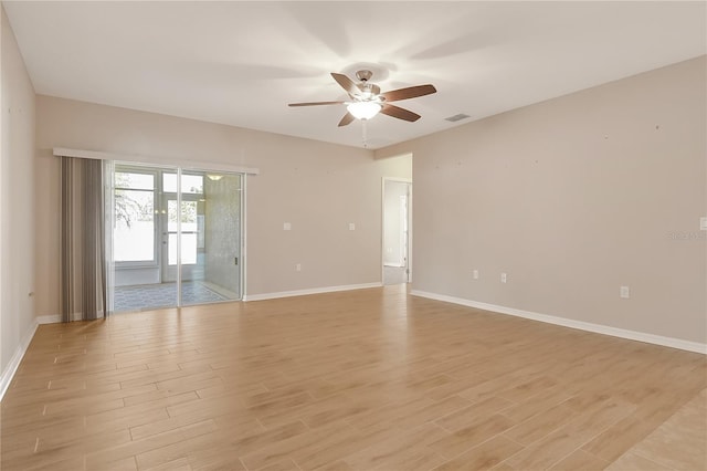 empty room with baseboards, a ceiling fan, visible vents, and light wood-style flooring