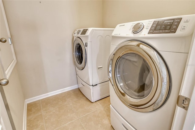 laundry area with baseboards, washer and dryer, laundry area, and light tile patterned floors