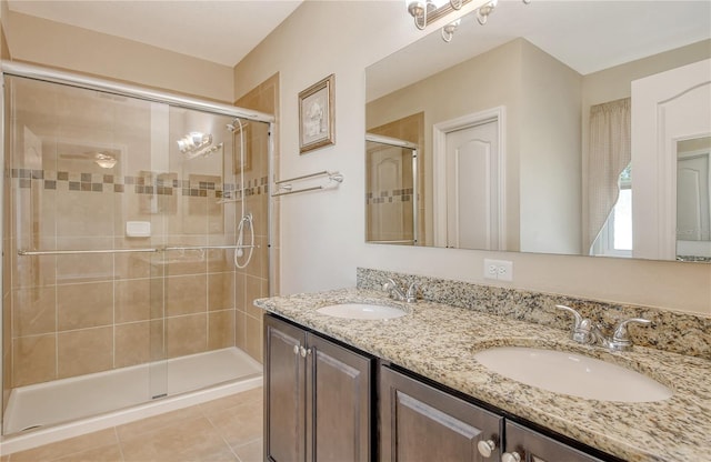 bathroom featuring double vanity, tile patterned floors, a stall shower, and a sink