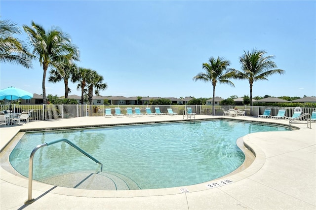 community pool with a patio area and fence