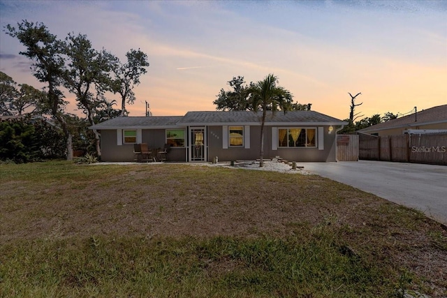 single story home featuring concrete driveway, stucco siding, fence, and a front lawn