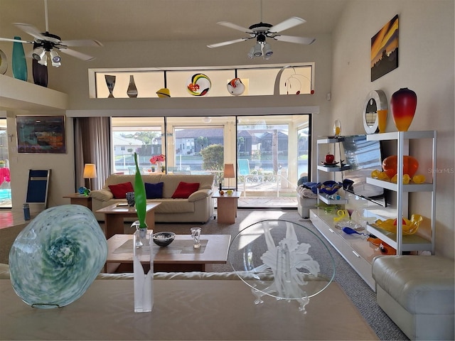 living area with a towering ceiling, ceiling fan, and a healthy amount of sunlight