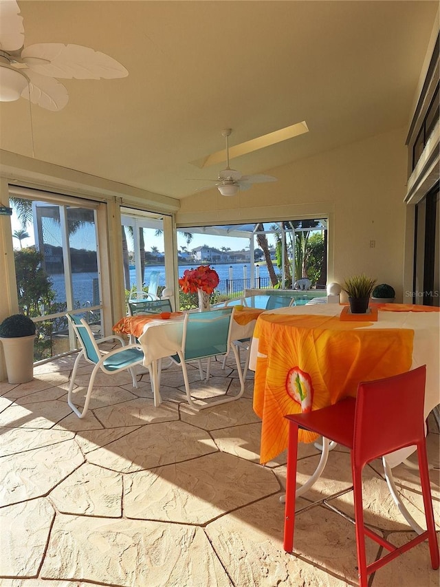 view of patio with a water view, a ceiling fan, outdoor dining area, and a pool