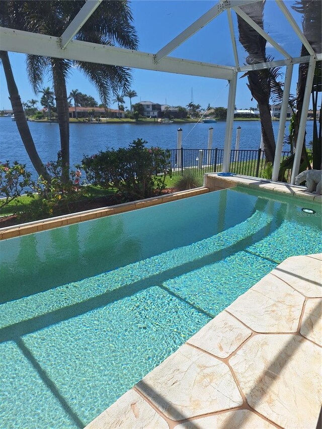 outdoor pool featuring a water view, a lanai, and fence