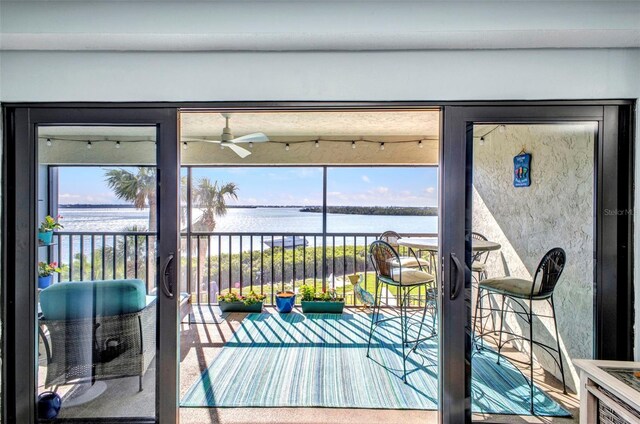 1701 Beach Rd Unit 305, Englewood, FL 34223 - doorway with a water view, a ceiling fan, carpet flooring, and a healthy amount of sunlight