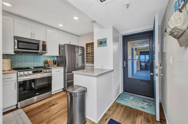1701 Beach Rd Unit 305, Englewood, FL 34223 - kitchen with recessed lighting, white cabinetry, decorative backsplash, light wood finished floors, and appliances with stainless steel finishes