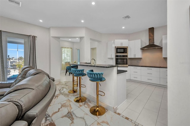 4213 Gardner Dr, Port Charlotte, FL 33952 - kitchen featuring stainless steel oven, wall chimney exhaust hood, open floor plan, built in microwave, and a breakfast bar