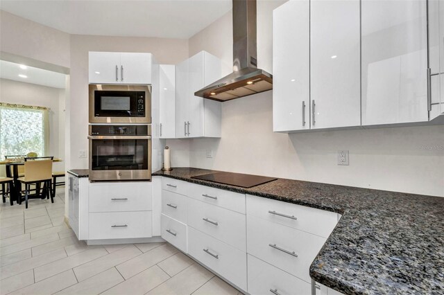 4213 Gardner Dr, Port Charlotte, FL 33952 - kitchen with black appliances, wall chimney range hood, white cabinets, dark stone countertops, and light tile patterned floors
