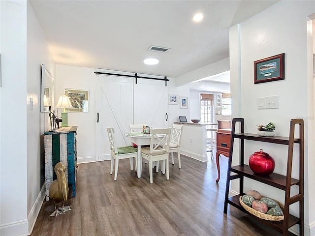 582 Ridgewood St NW, Port Charlotte, FL 33952 - dining space featuring a barn door, wood finished floors, baseboards, and recessed lighting