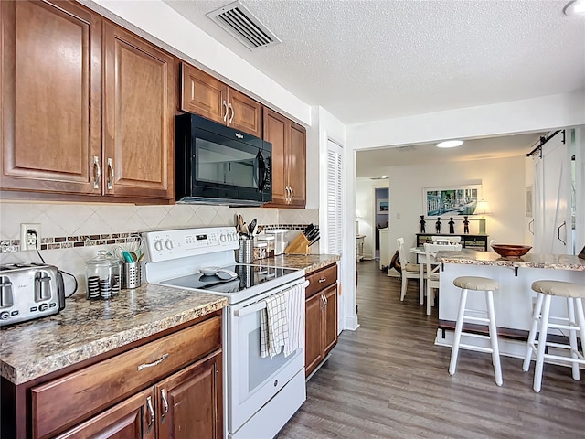 582 Ridgewood St NW, Port Charlotte, FL 33952 - kitchen with white electric stove, black microwave, a kitchen breakfast bar, tasteful backsplash, and wood finished floors