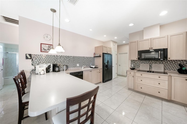 kitchen featuring black appliances, light brown cabinets, a peninsula, a sink, and backsplash