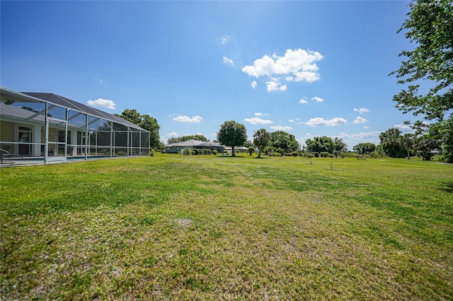 view of grassy yard with glass enclosure