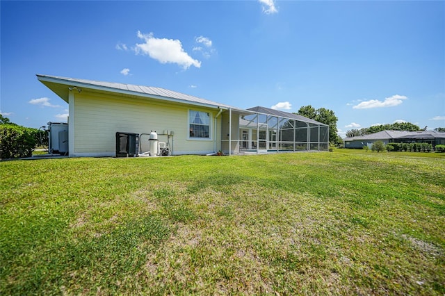 back of house featuring a yard, glass enclosure, and metal roof