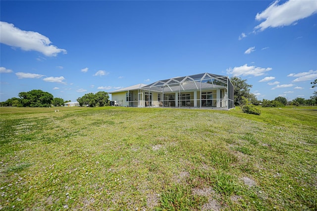 rear view of house featuring a lawn and glass enclosure