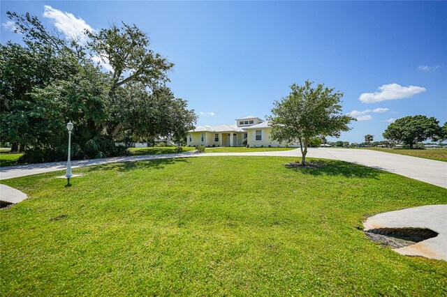 view of front of house featuring curved driveway and a front lawn