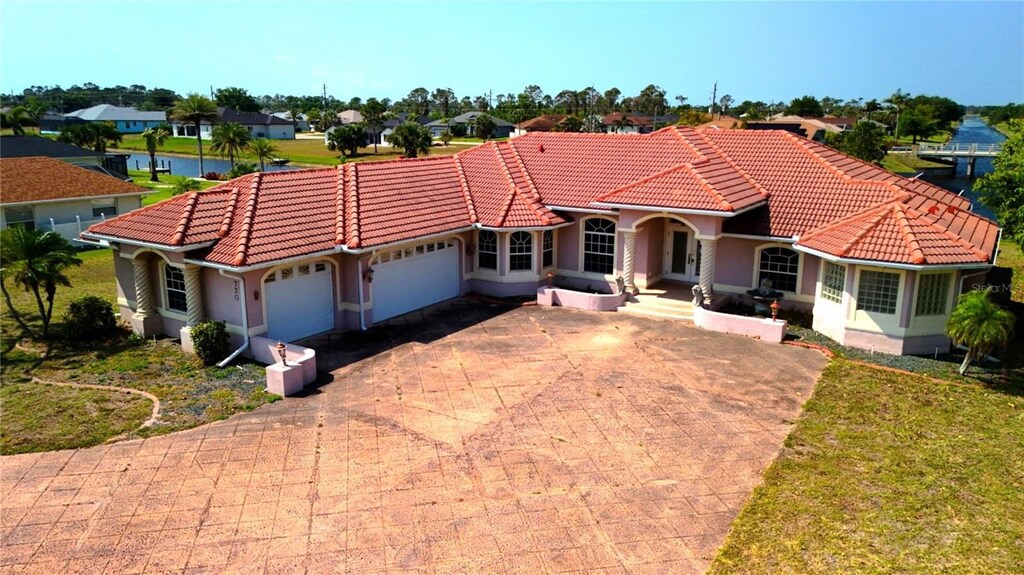 730 Boundary Blvd, Rotonda West, FL 33947 - mediterranean / spanish-style house with decorative driveway, an attached garage, a residential view, and a tile roof
