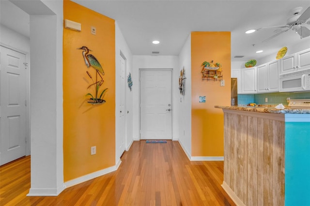 corridor featuring baseboards, recessed lighting, and light wood-style flooring
