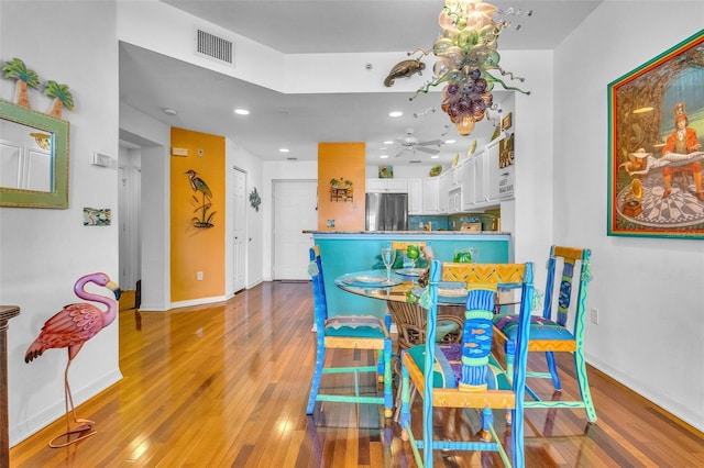 dining area featuring baseboards, a ceiling fan, wood finished floors, and visible vents
