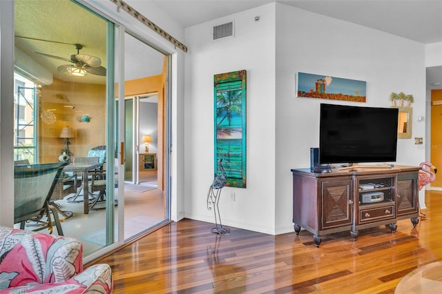 living room featuring baseboards, ceiling fan, wood finished floors, and visible vents